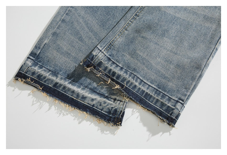 Close-up of two jean leg hems showing a washed finish, contrast stitching, and loose raw edges.