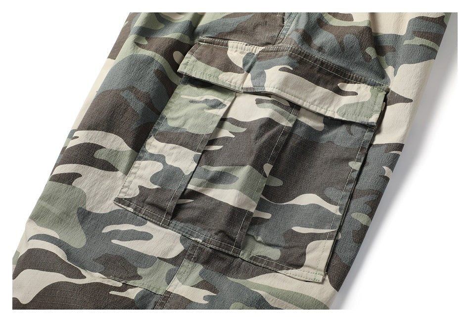 Close-up of a large flap cargo pocket on camouflage pants, shown against a white background.