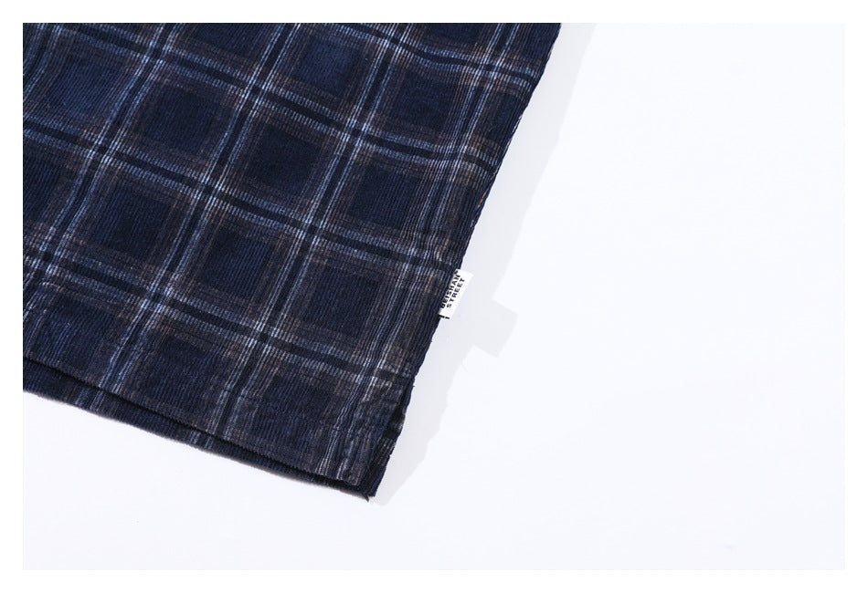 Close-up of the hem of a dark navy plaid garment with a small sewn-in label.