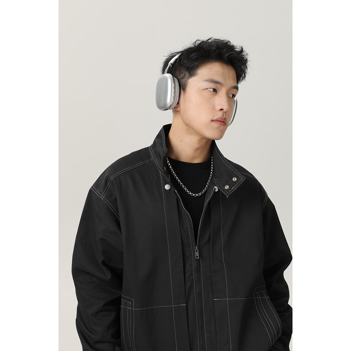 Model wearing a black jacket with contrast stitching, a stand collar, and a zip front.
