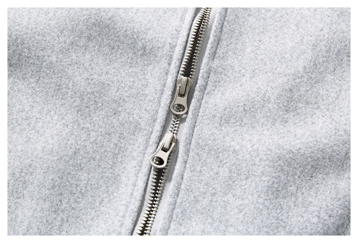 Close-up of the light gray coat's metal front zipper with two pull sliders.