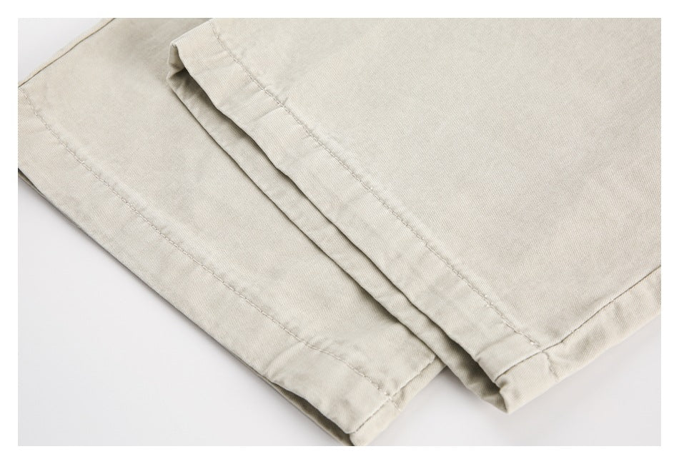 Close-up of overlapping light beige trouser legs showing stitched hems.