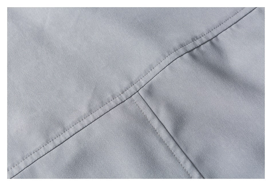 Close-up of intersecting stitched seams on light gray fabric.