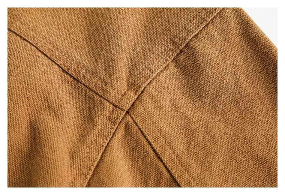 Close-up showing intersecting seams on textured camel-brown garment fabric.