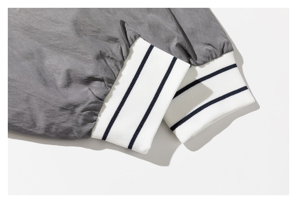 Close-up of gray jacket sleeves ending in white ribbed cuffs with two dark stripes.