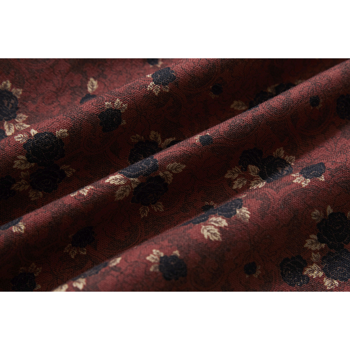 Macro view of burgundy shirt fabric with a black and cream floral print.