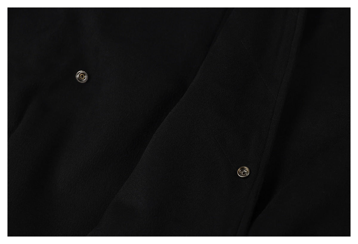 Close-up of a black jacket's overlapping front placket with two metal snap fasteners.