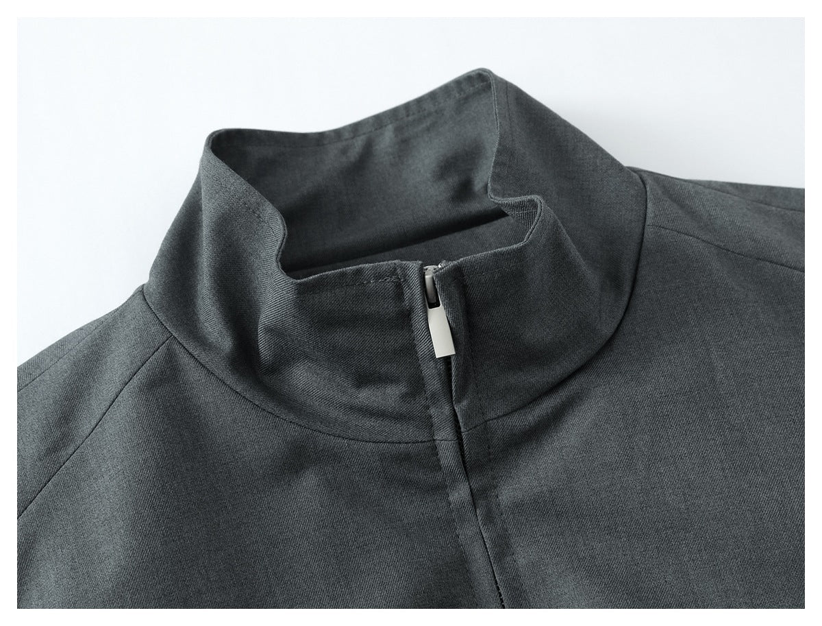 Close-up of a dark gray garment's raised collar and front zipper with a silver pull.