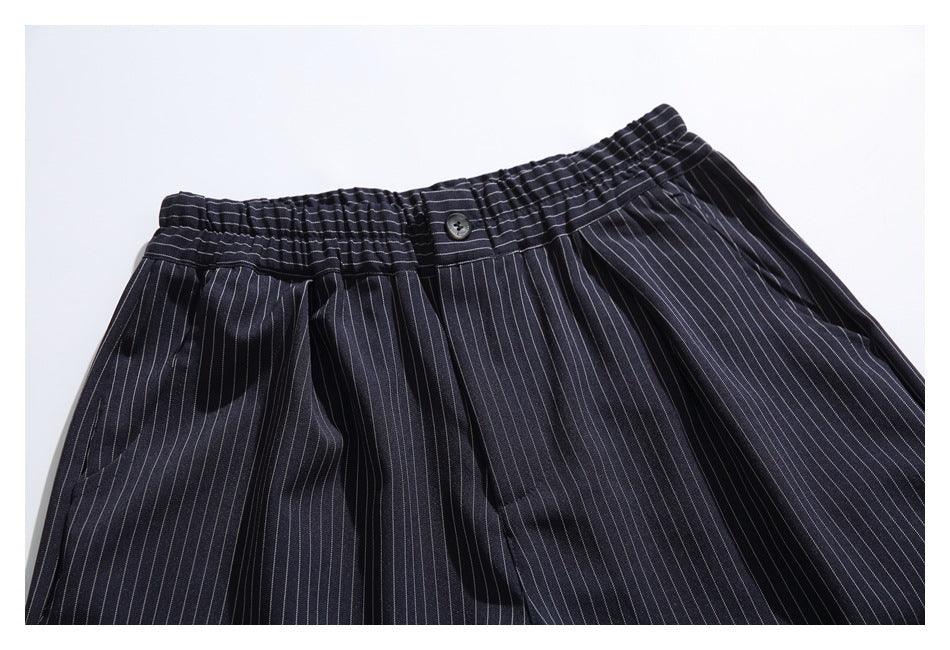 Front close-up of dark navy pinstripe shorts showing the elasticated waistband, button, pleats and pocket openings.