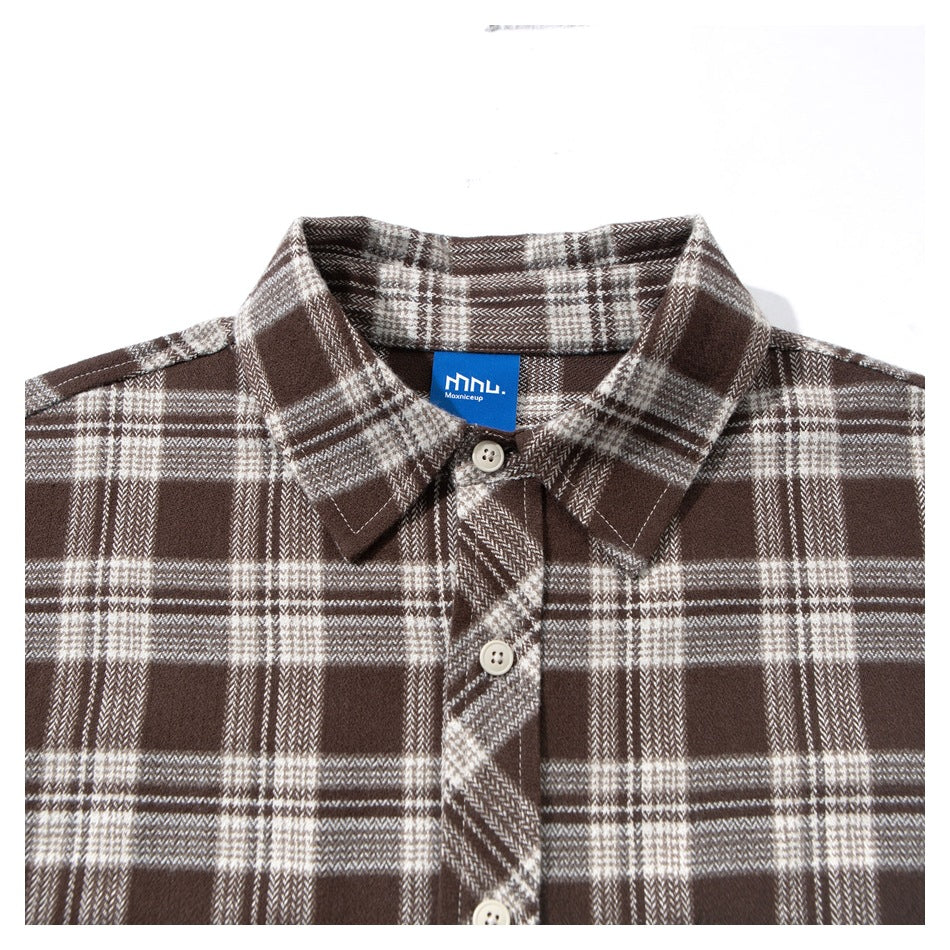 Close-up of a brown and cream plaid shirt's collar, button placket, and blue neck label.