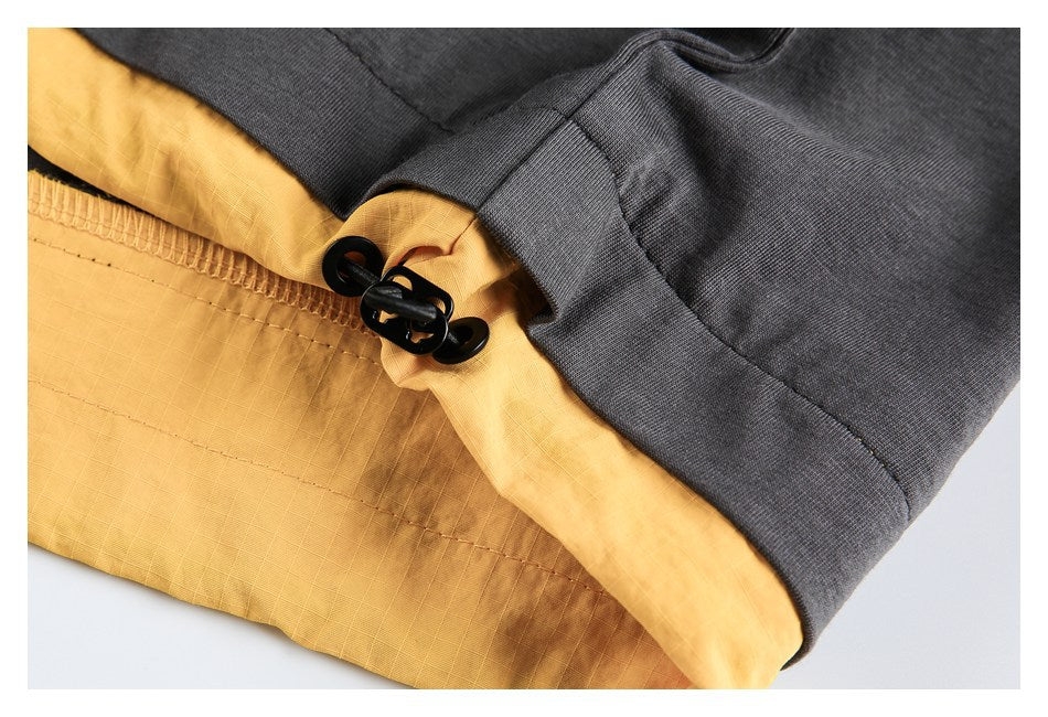 Close-up of a charcoal garment with a mustard-yellow inner layer and black drawstring toggles.