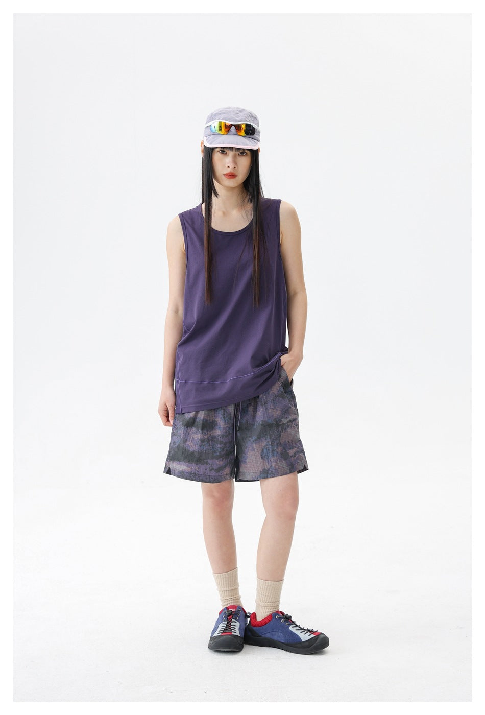 Front view of a model wearing a dark purple sleeveless top and purple-gray patterned shorts.