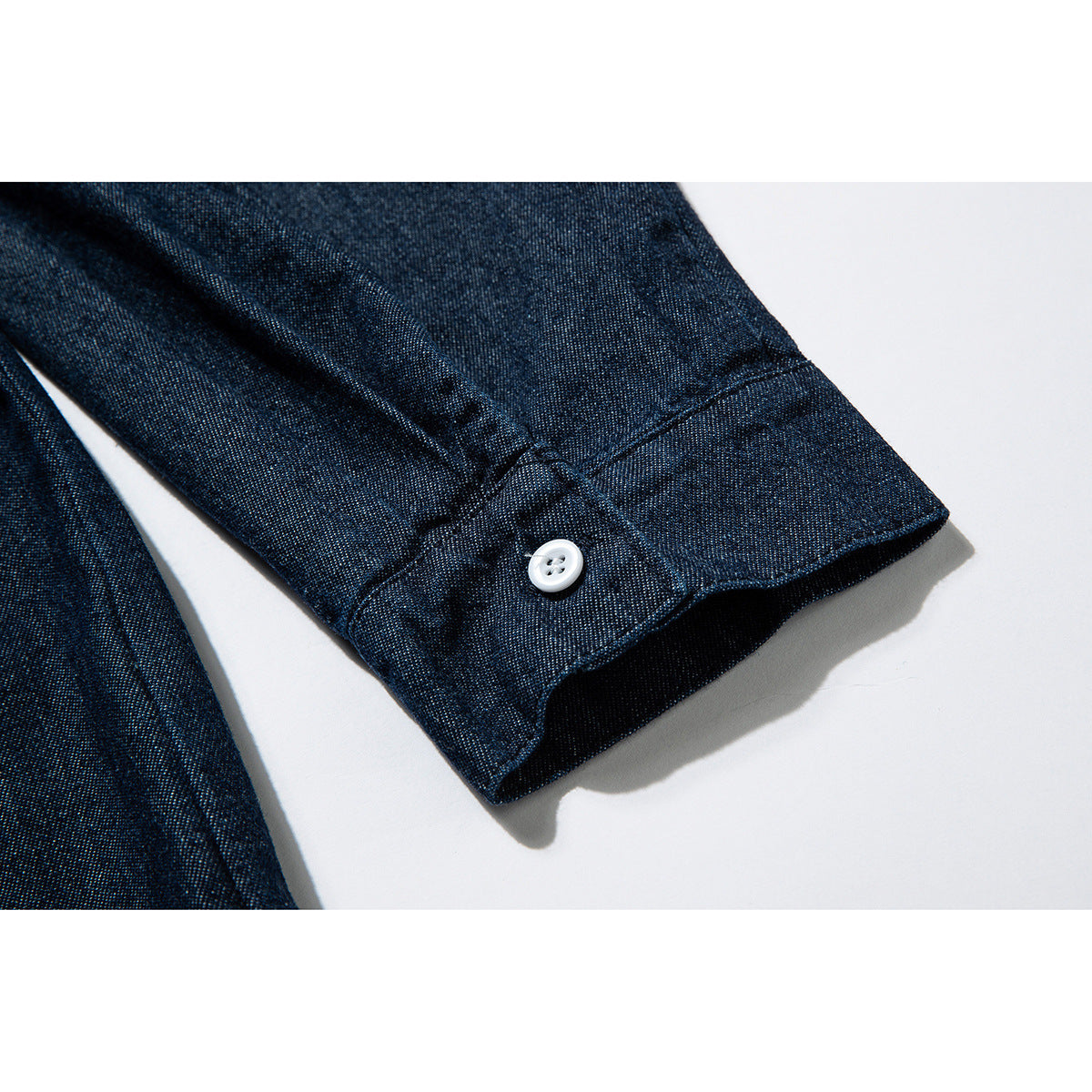Close-up of a dark indigo shirt sleeve cuff with a white button.