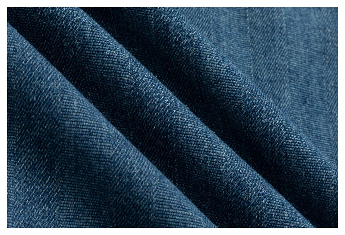 Close-up of dark blue denim folded into diagonal ridges, showing its twill texture.