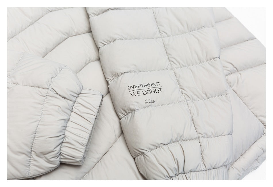Close-up of a light gray quilted jacket sleeve with printed text reading “OVERTHINK IT WE DO NOT.”