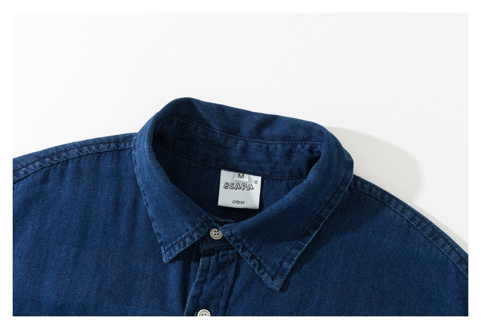 Close-up of a navy blue shirt collar, top buttons, and woven label.