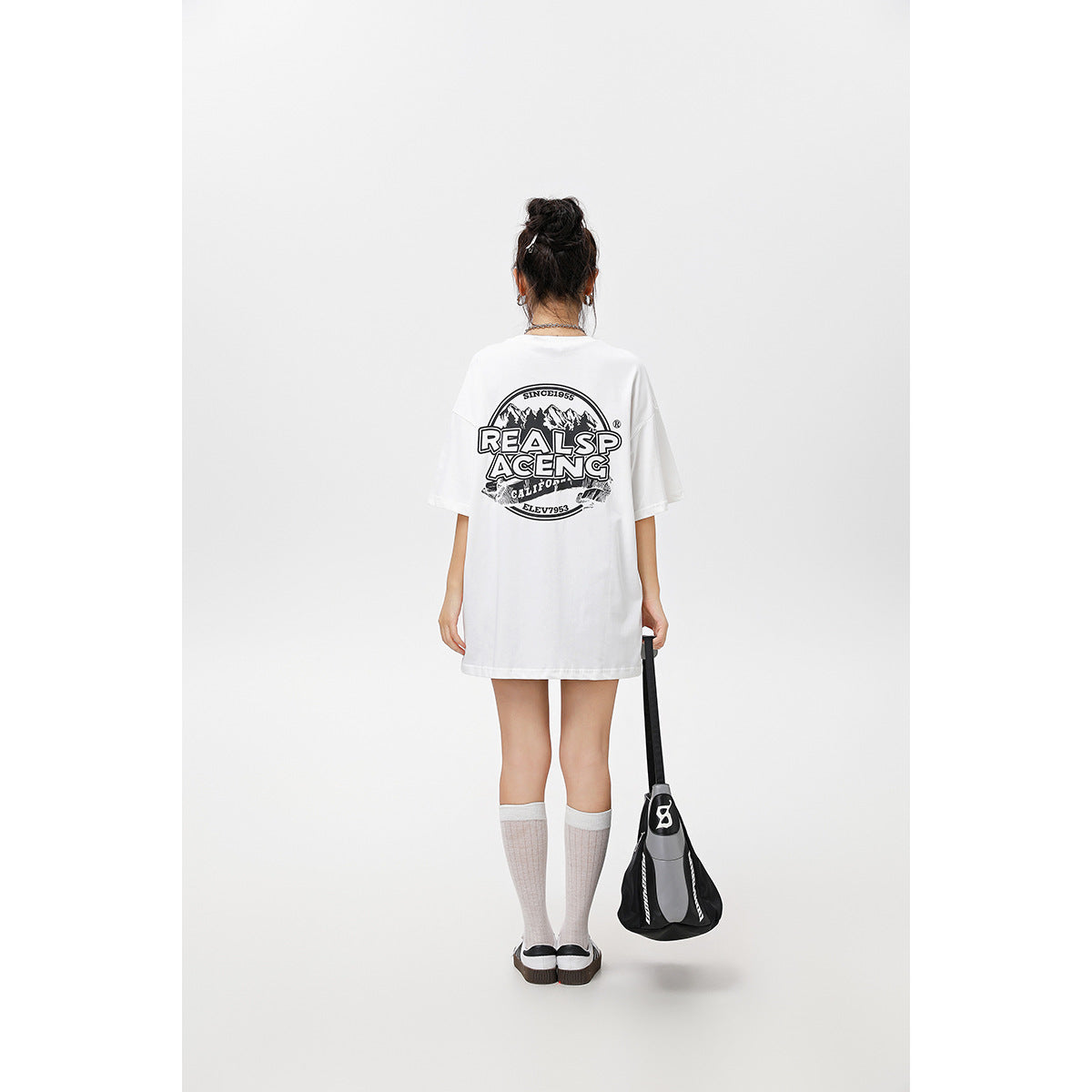 Back view of a model wearing an oversized white T-shirt with a large black graphic print.