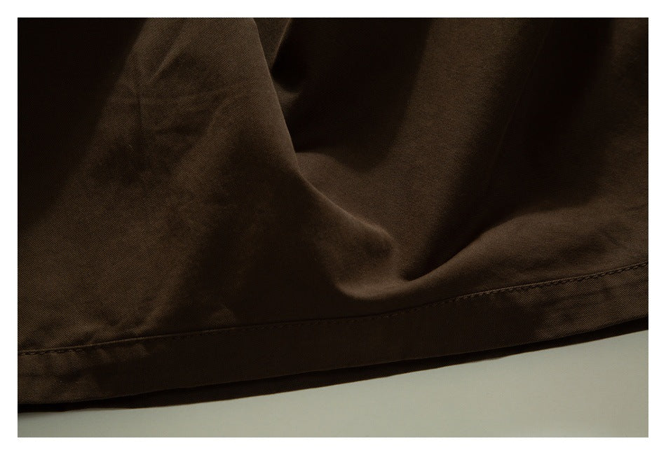 Close-up of dark brown trouser fabric and stitched hem.