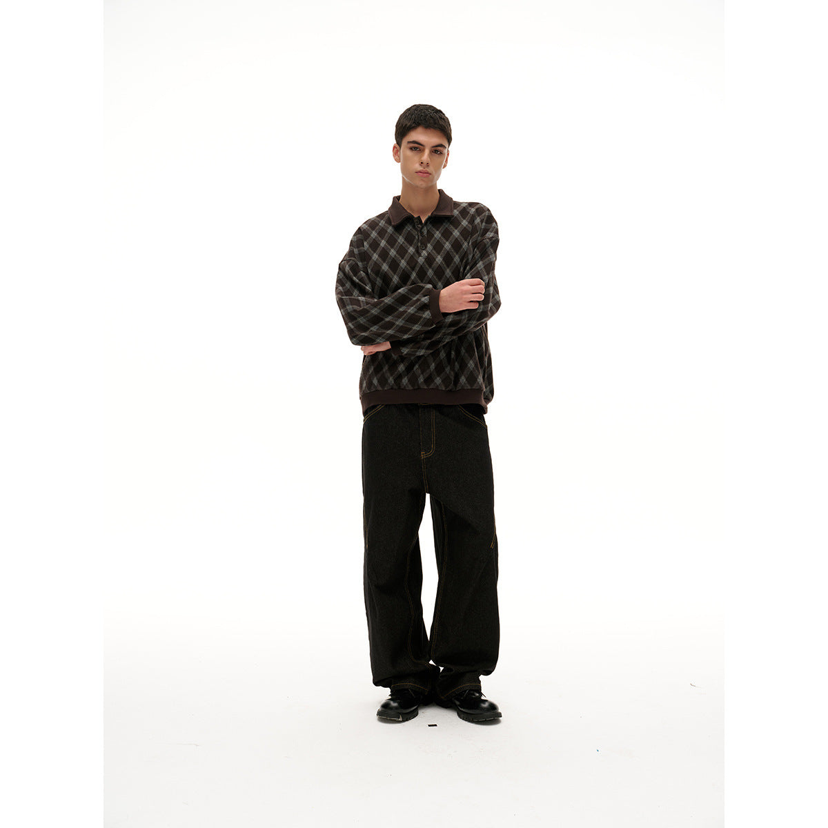 Model wearing a dark brown and gray diamond-check collared pullover and black wide-leg pants, arms crossed.