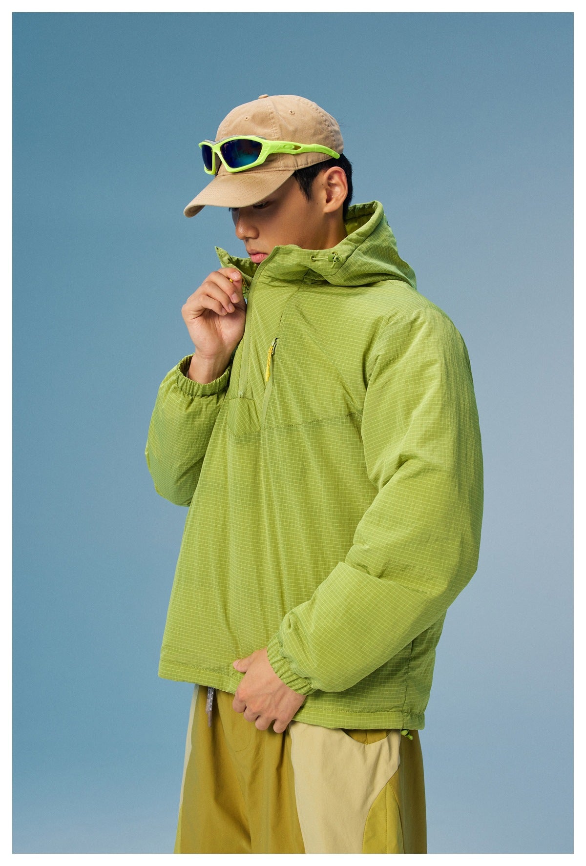 Model wearing a lime green grid-pattern hooded pullover jacket with a front zipper and elastic cuffs.