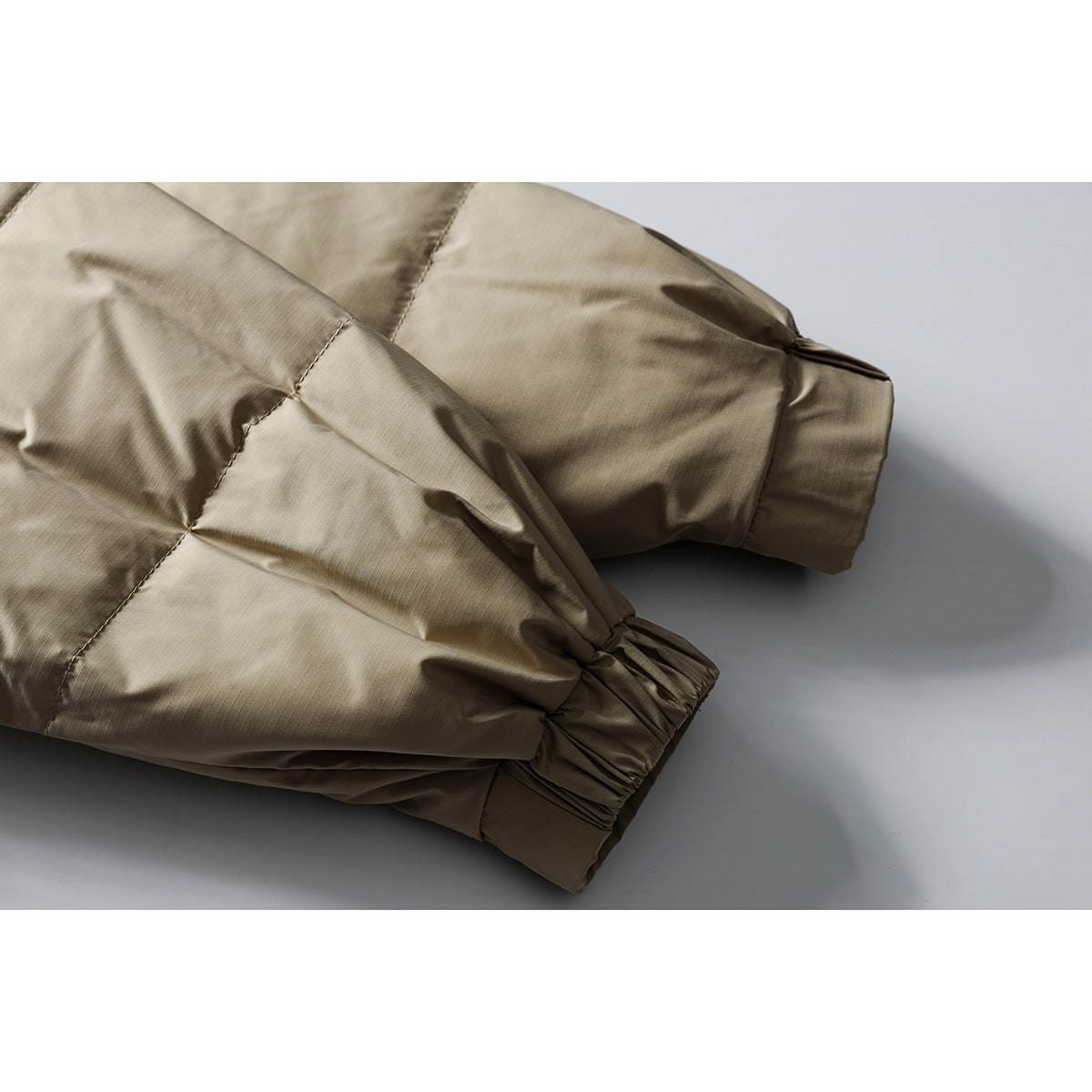 Close-up of the taupe puffer jacket's quilted sleeve and elastic cuff.