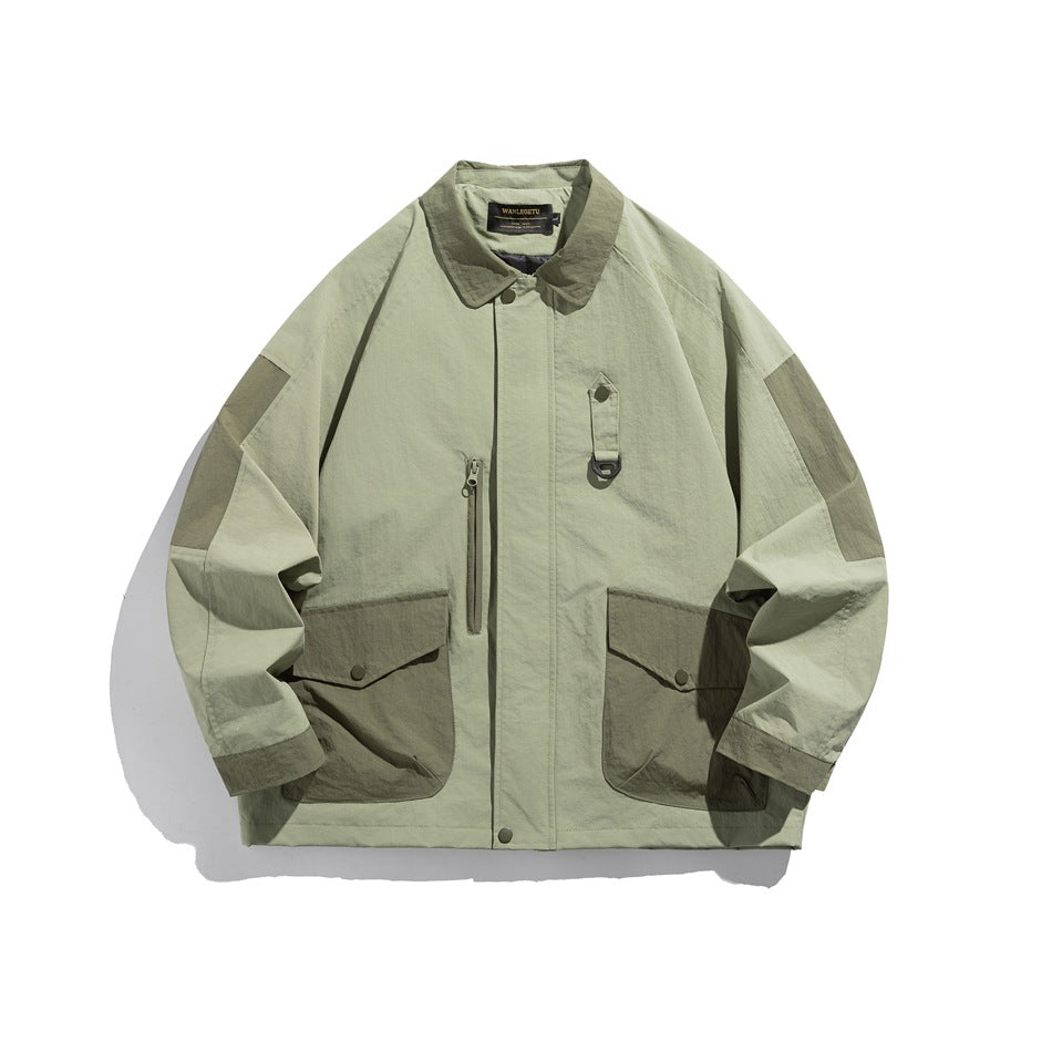 Sage green collared jacket with darker green contrast pockets, shoulder panels and cuffs, front view on white