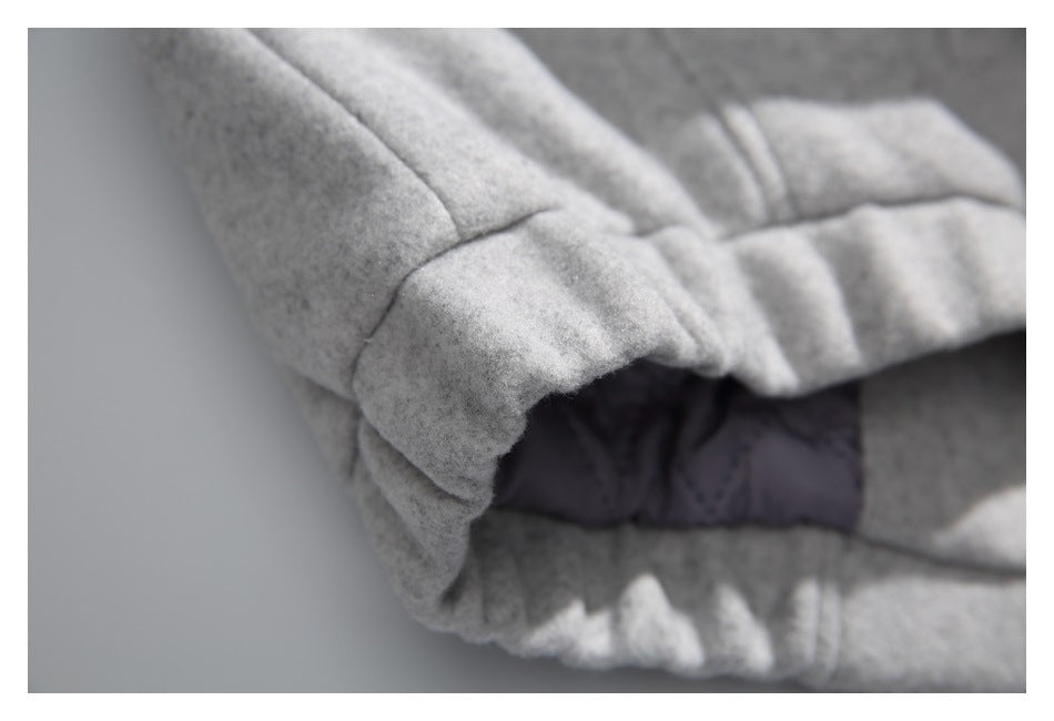 Close-up of a light gray cuff and seam, with dark quilted lining visible underneath.