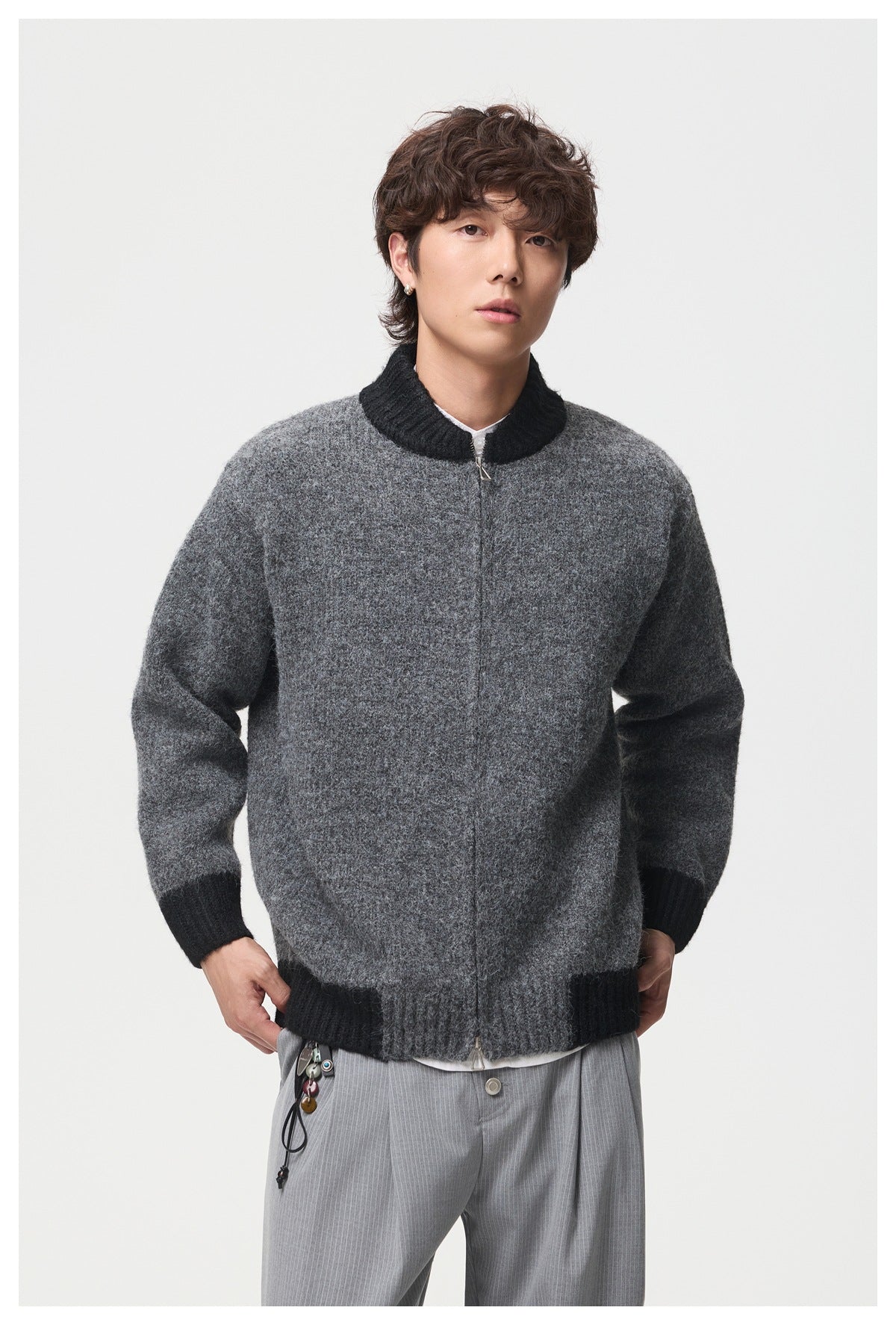 Model wearing the dark gray zip-up knit jacket with black trim, front view, with gray striped trousers