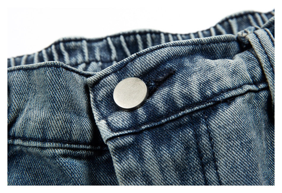 Close-up of the blue denim waistband and silver metal button.