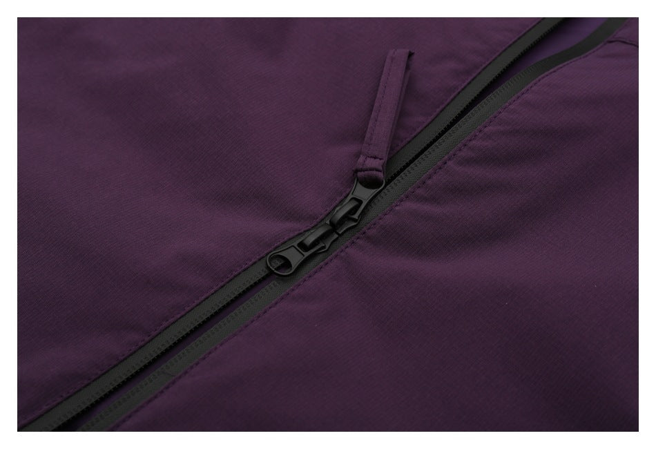 Close-up of black zipper sliders and pull tabs on a purple garment.