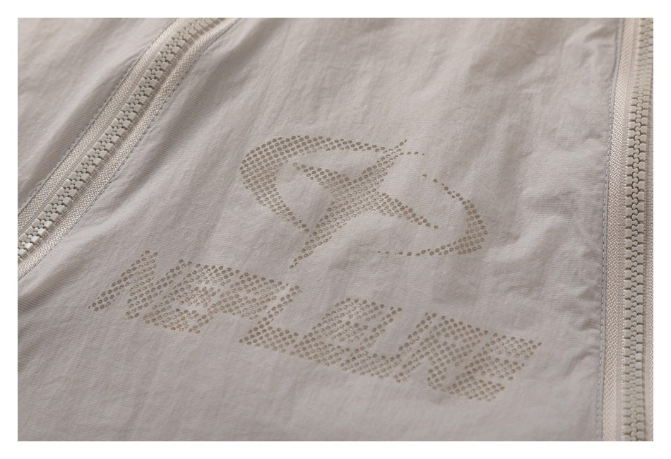 Close-up of dotted graphic lettering on a light taupe jacket between two zippers.