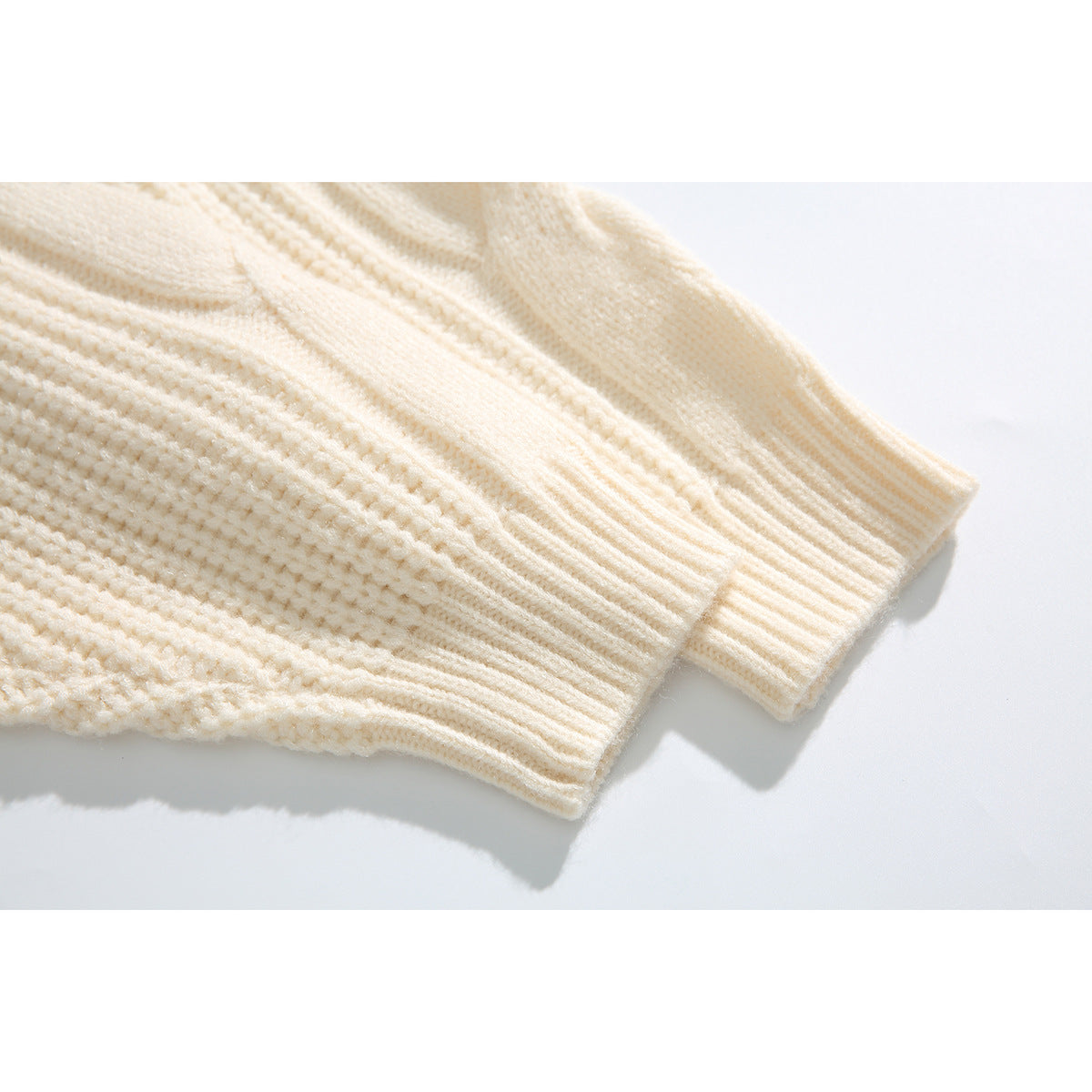 Close-up of the ivory sweater's textured knit and ribbed sleeve cuffs.
