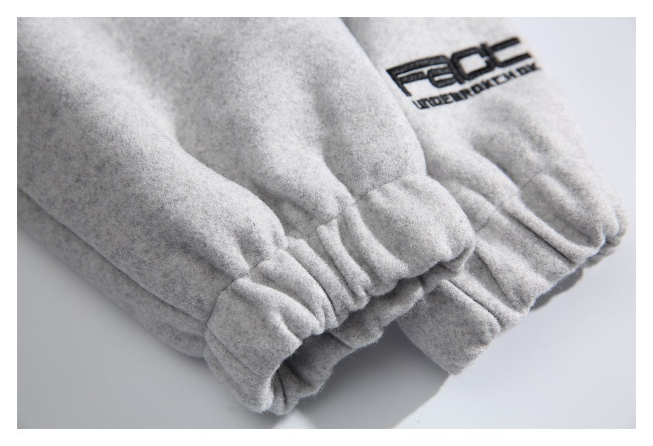 Close-up of light gray gathered cuffs with a black embroidered wordmark on the fabric.