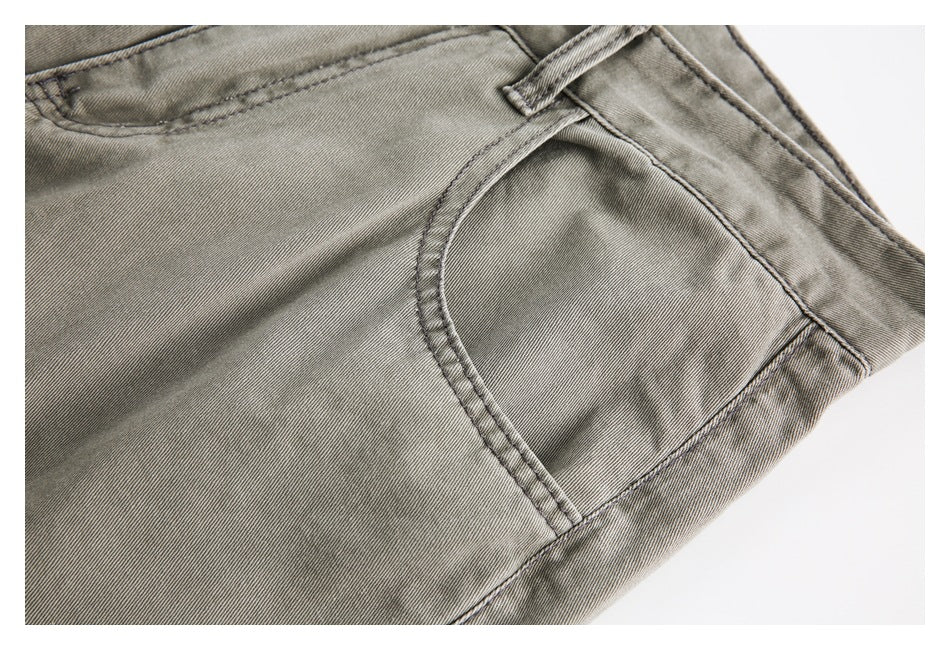 Close-up of a curved front pocket and belt loop on gray-olive trousers.