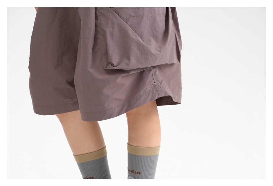 Close-up of the mauve shorts' oversized side cargo pocket and hem, worn with gray socks.