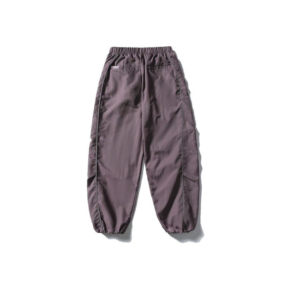 Mauve relaxed pants shown from the back, with an elastic waist, two pockets, side piping and gathered cuffs.