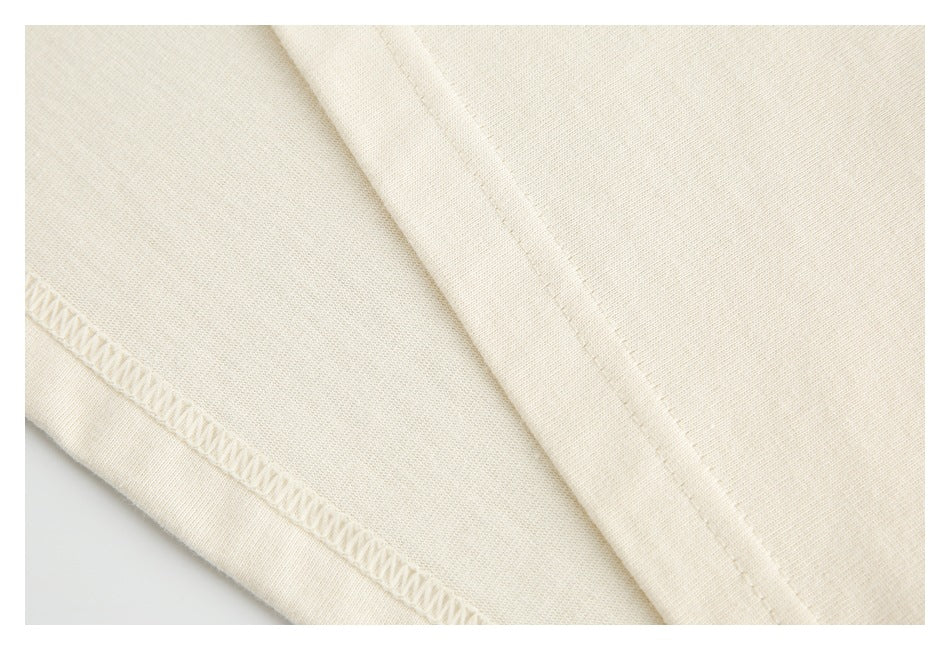 Close-up of cream garment fabric showing an overlocked seam and a stitched edge.