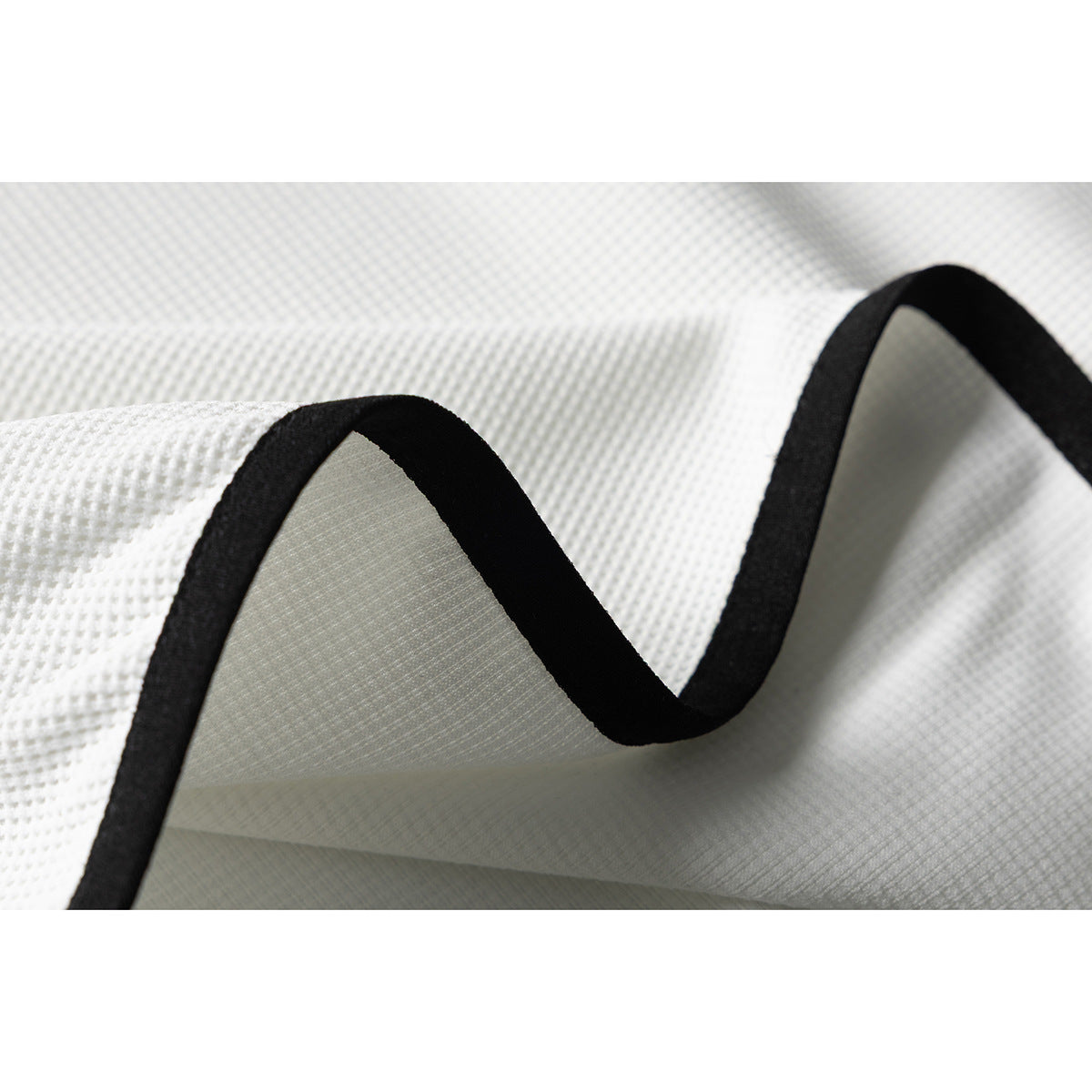 Close-up of white textured fabric folded to show its black edge binding.
