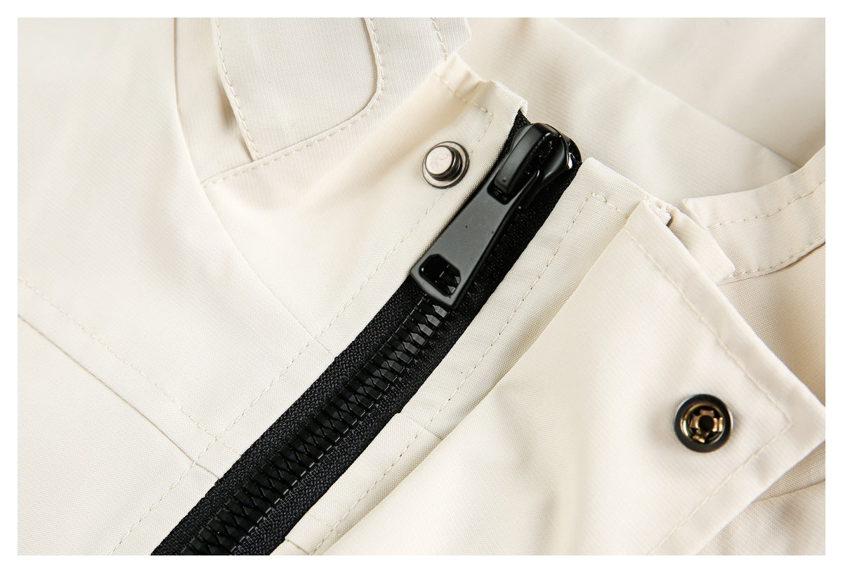 Close-up of a black zipper and metal snaps on a cream garment.
