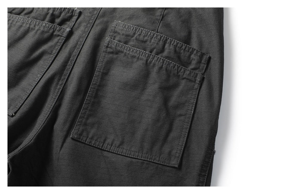 Close-up of a large stitched patch pocket on dark charcoal pants.
