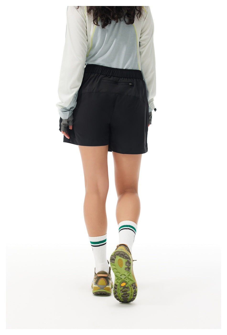 Back view of a model wearing black athletic shorts with an elastic waistband and a small zippered back pocket.