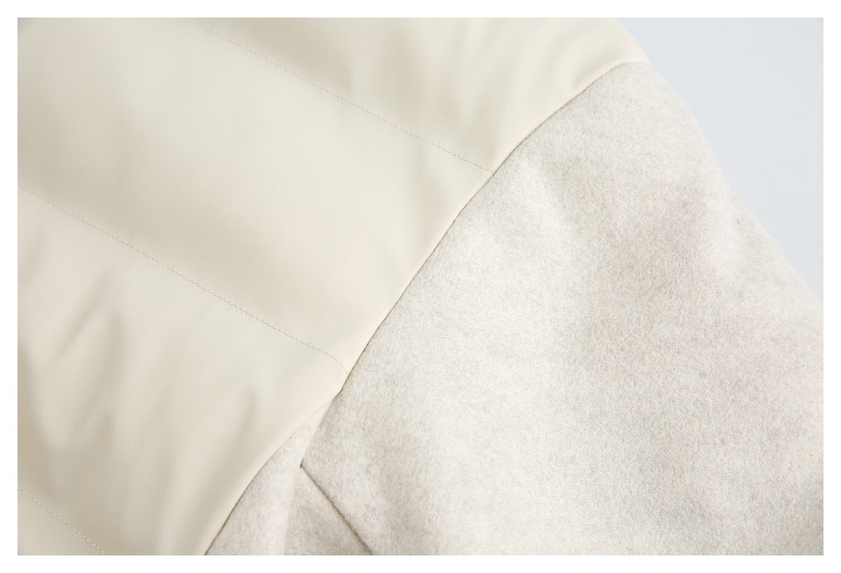 Close-up of the ivory jacket's quilted body panel and light gray sleeve seam.