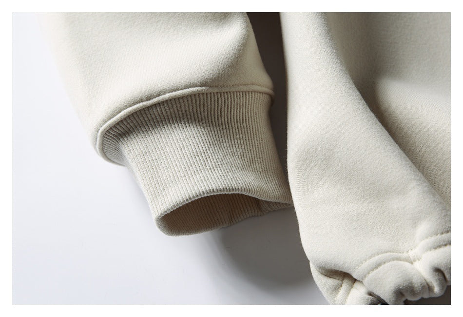 Close-up showing a ribbed cuff and gathered hem on a cream sweatshirt.