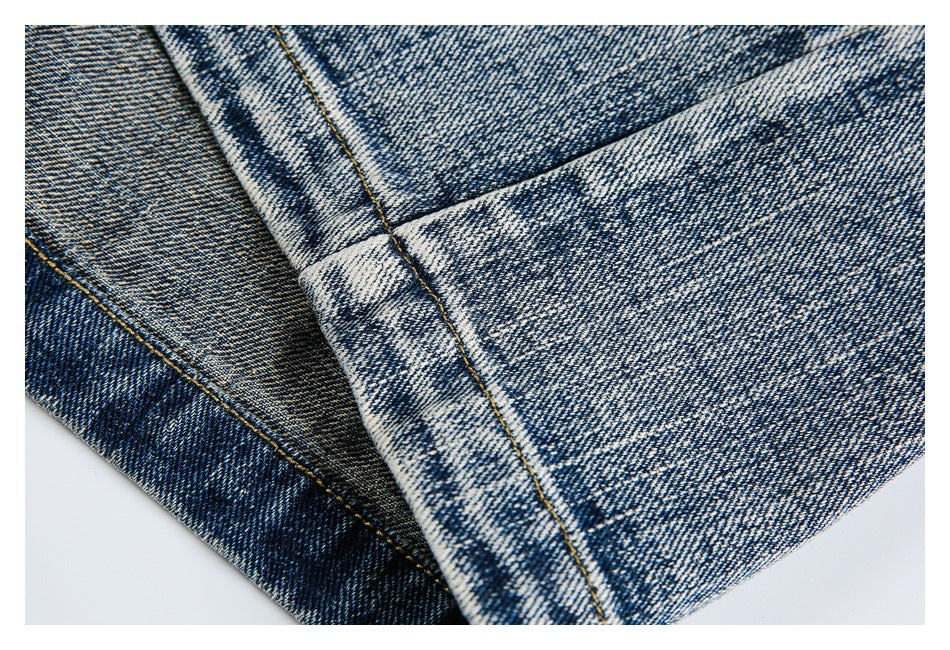 Close-up of the faded blue jeans’ stitched leg hem and denim seam.