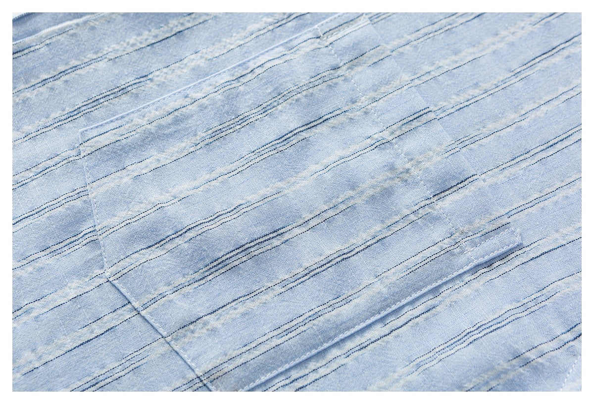Close-up of light blue striped shirt fabric with a stitched panel seam.
