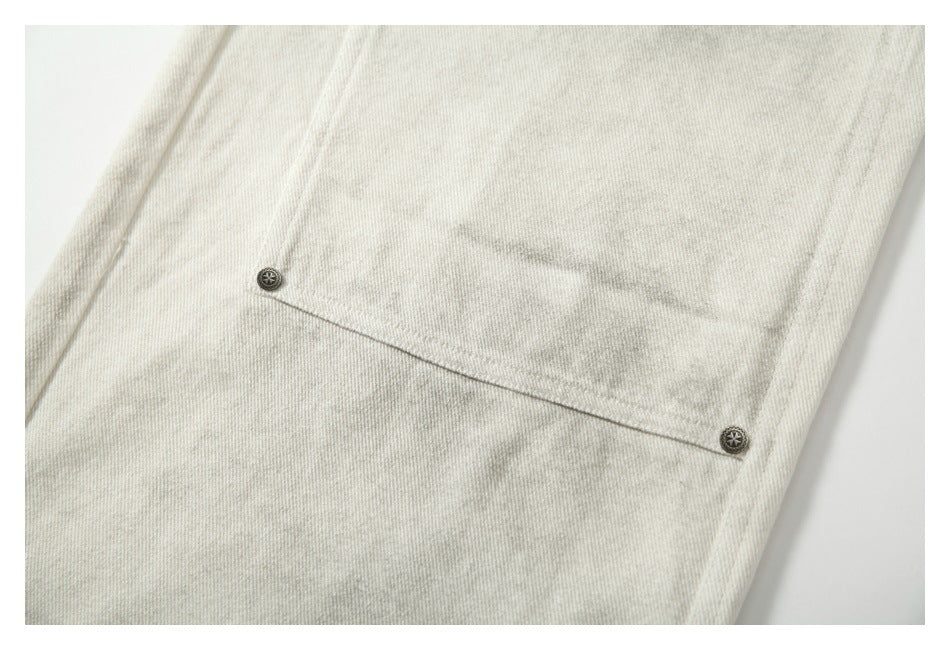Close-up of a horizontal buttoned pocket flap on cream-gray mottled trousers.