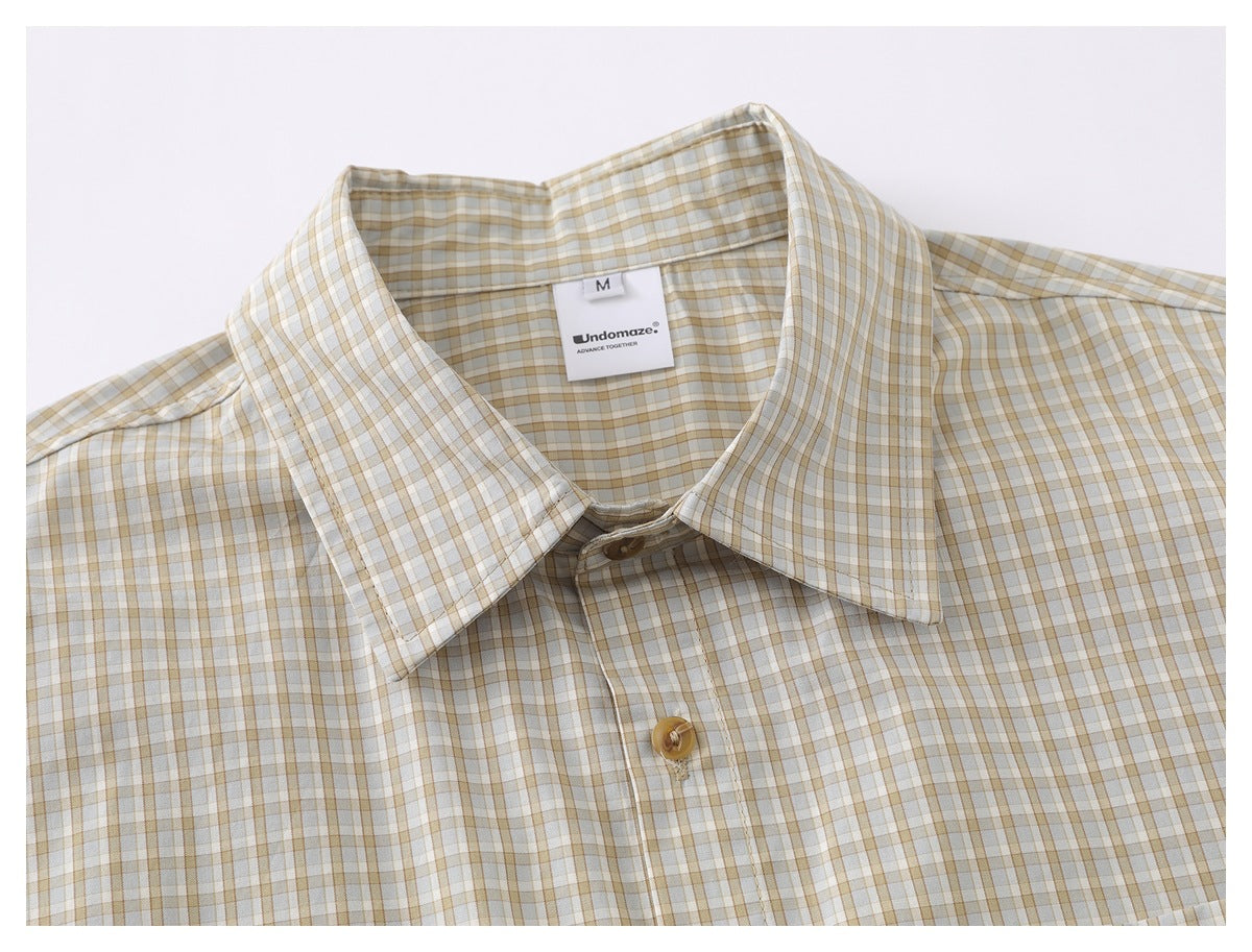 Close-up of the cream checked shirt's pointed collar, front button, and neck label.