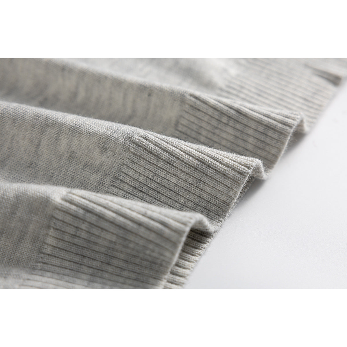 Close-up of the light gray knit polo's ribbed sleeve cuffs and fabric texture.