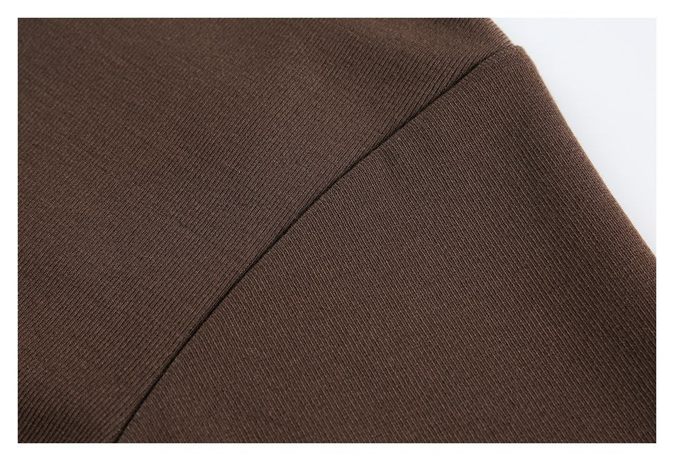 Close-up of a curved shoulder seam on brown rib-knit fabric.
