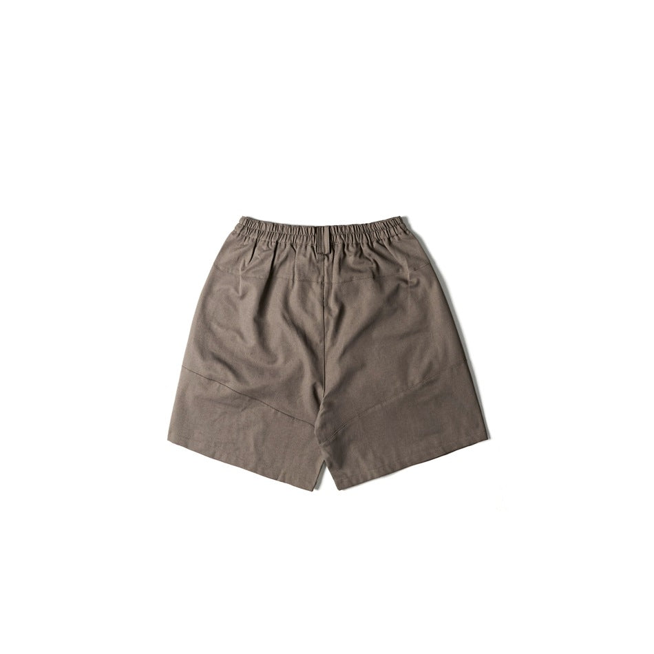 Back view of taupe-brown shorts with elastic waistband and diagonal panel seams, flat lay